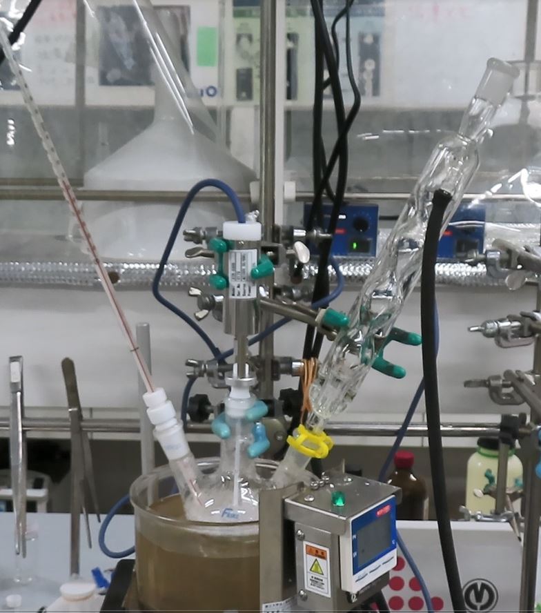 高分子の合成実験。3つ口フラスコに温度計、攪拌機、冷却管を取り付けて、オイルバス（油浴）で加熱して重合反応を実施します。