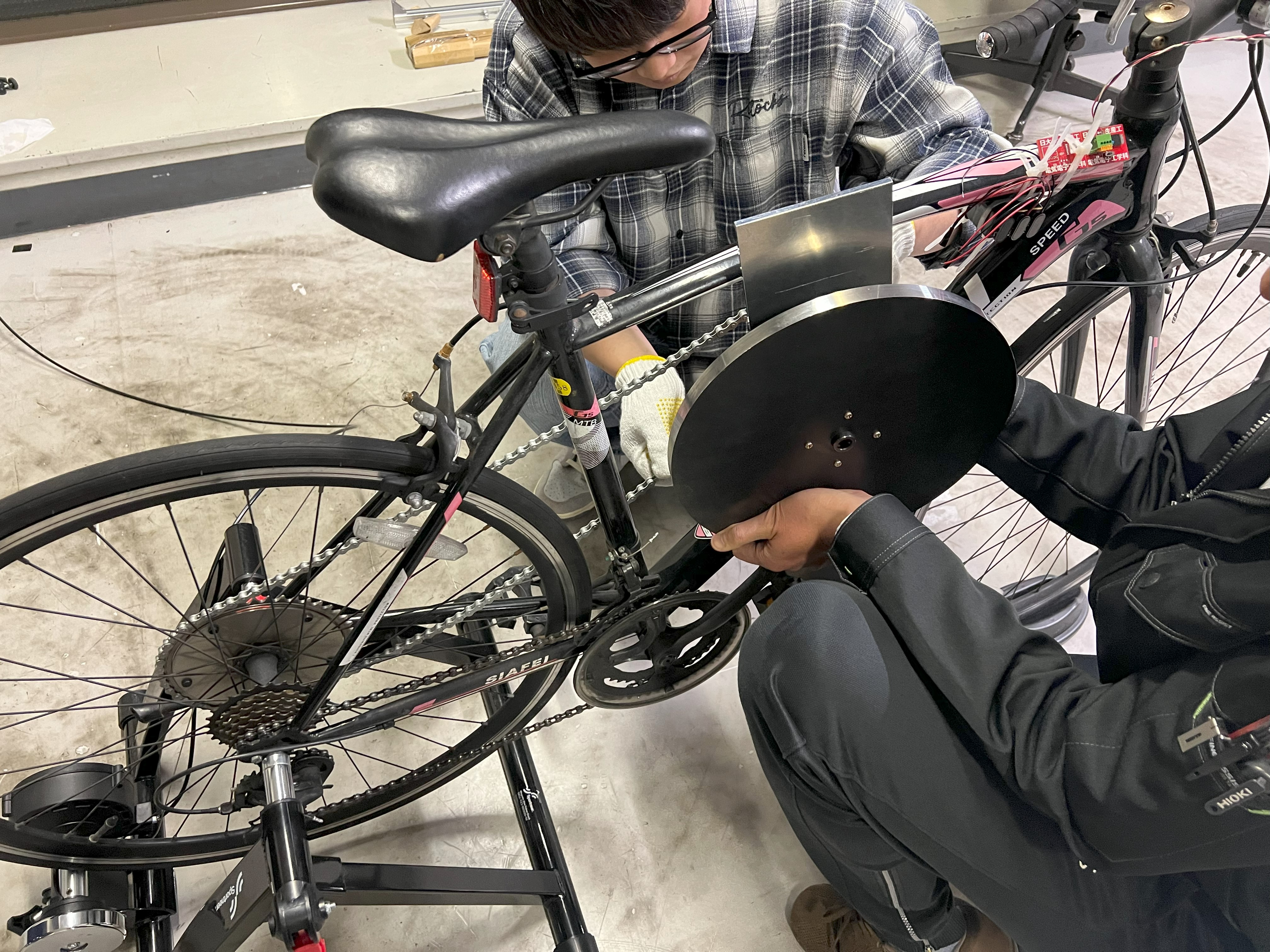 フライホイール式アシスト自転車の製作過程でのフライホイール装着作業。これが実現すればバッテリーとモーターが不要なアシスト自転車が完成します。