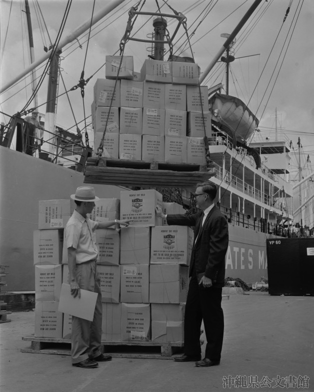 沖縄では、アメリカの宗教団体から寄贈された物資により学校給食が実施された。写真は入荷された学校給食用ドライミルク(沖縄県公文書館所蔵、1964年4月28日撮影、写真番号260CR-54_0620-01)。
