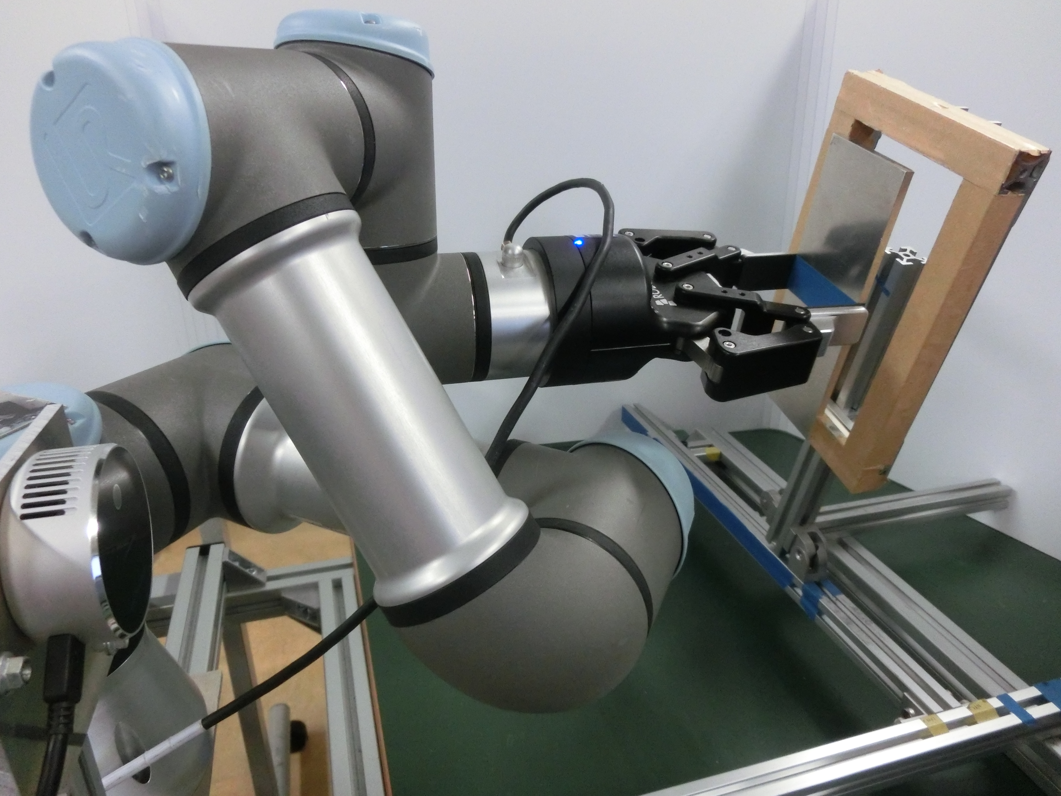 ロボットアームで枠に板状物体を差し込む様子。窓枠のように斜めから滑り込ませるような動きを自動的に生成する。