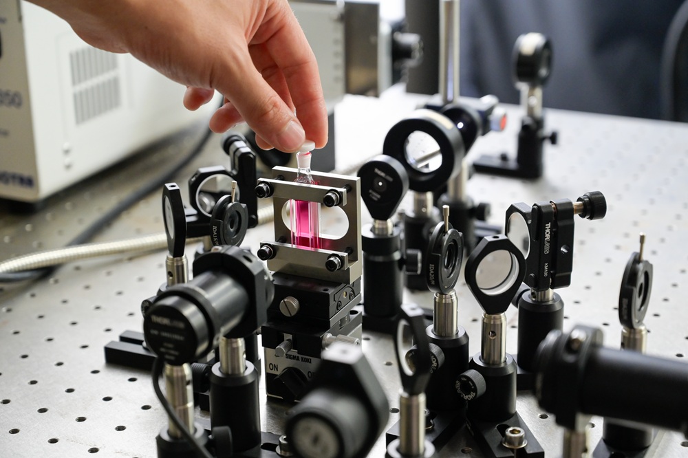 分子の光反応を測定する装置。中央の赤い液体に分子が溶けている。