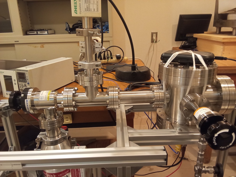 組み立てた装置を真空槽に設置した状態です。右側が真空槽で,、中央に真空計、左側に真空ポンプがあります。真空槽の上方に中性子の検出器を設置しています。