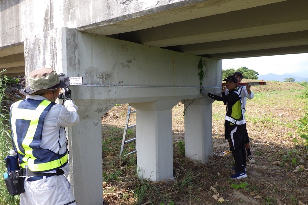 学生と一緒に研究対象の橋梁を測っている様子