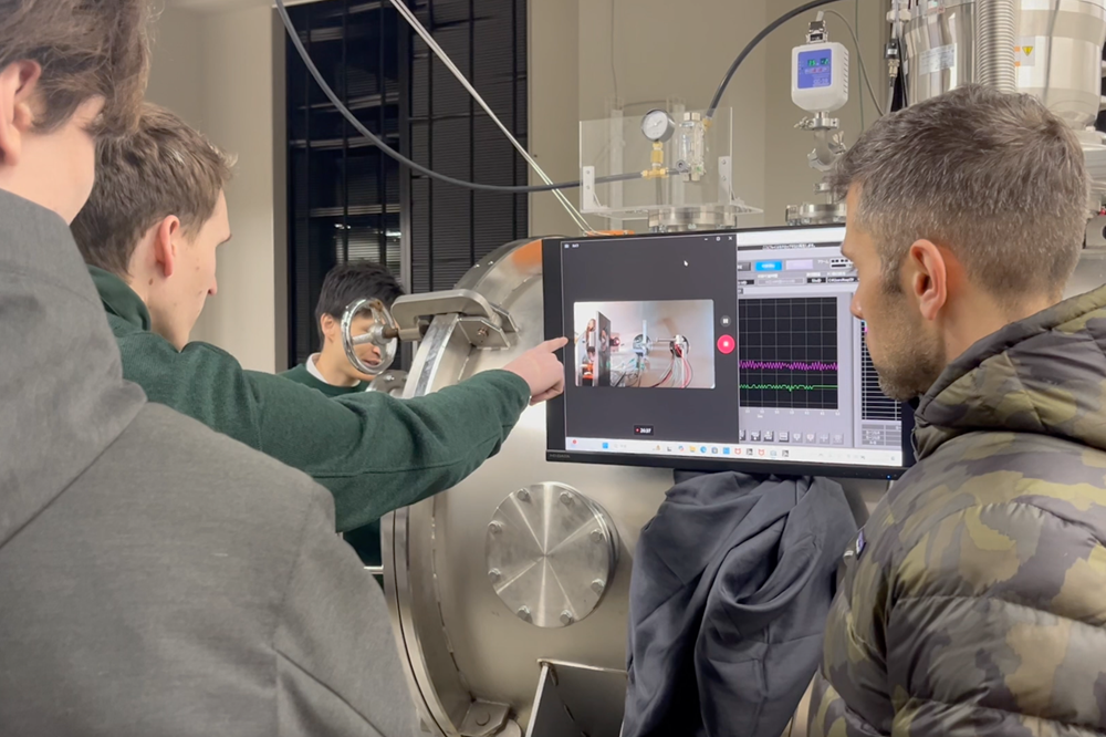 真空チャンバーの前で議論する様子。フランス、オーストリア、ブラジル、マレーシア、ドイツなどさまざまな国の留学生と関わりがあります。