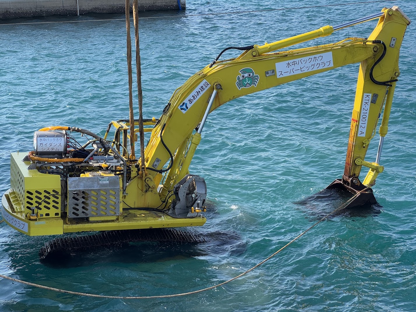 防波堤などの建設現場では、水中建設機械が活躍しています。しかし、水中ではGPSが使用できないため、超音波を用いた位置計測技術の研究を進めています。この写真は、試作した位置計測装置を水中バックホウに搭載し、測位実験を行った際の一コマです。実際の現場環境を理解しながら、実用性の高い技術へと発展させていくことを目指しています。