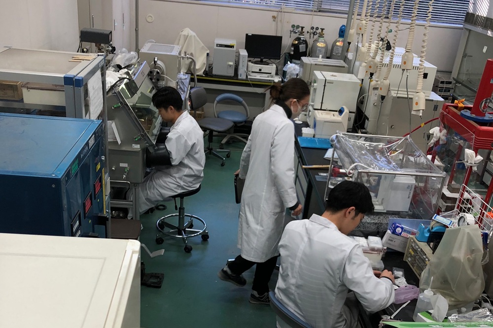 試料合成を行う実験室の様子。左側の学生は、湿気や酸素を遮断した雰囲気で試料調整している。