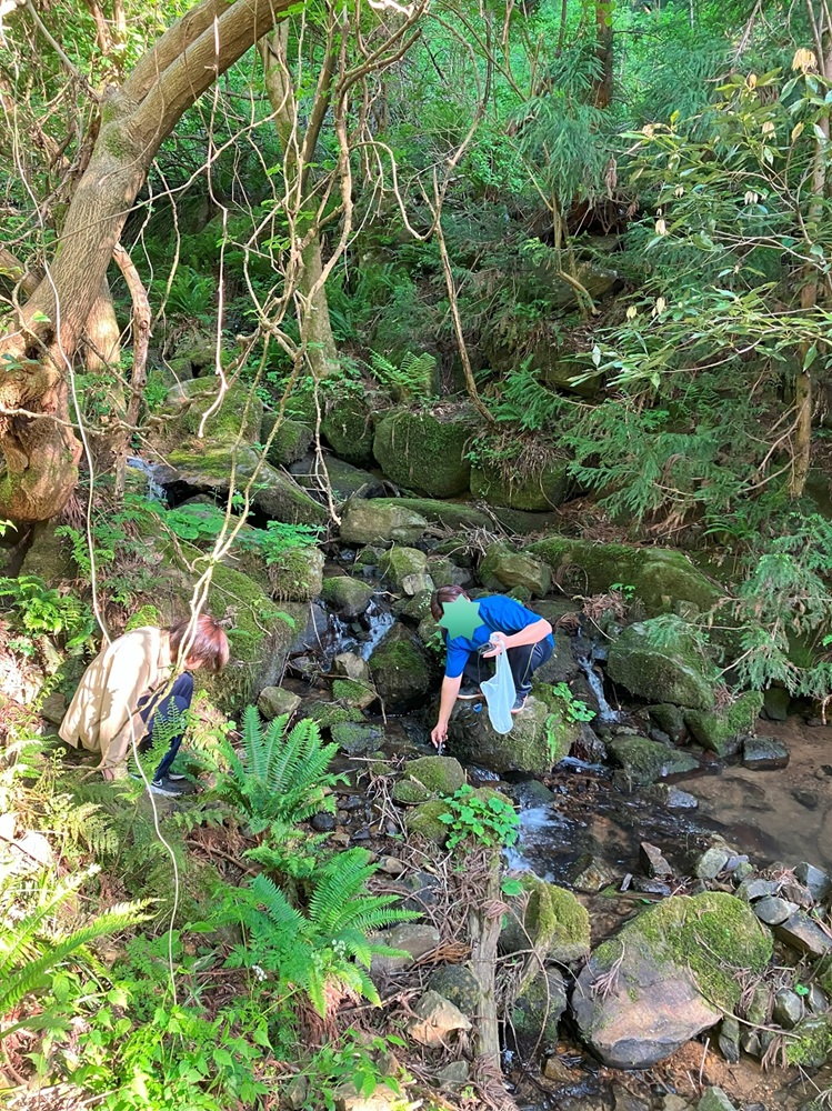 研究室の学生さんと渓流水調査をしている様子。現地で水のpHを測定し、水サンプルをボトルに採取して帰ります。