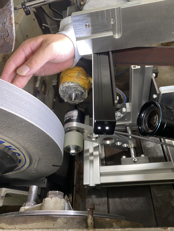 部品を磨いて綺麗にする機械（研削盤）には必ずといっていいほど砥石が装着されています。磨いた後の砥石表面を観察するための装置を開発し、その試運転を行っています。