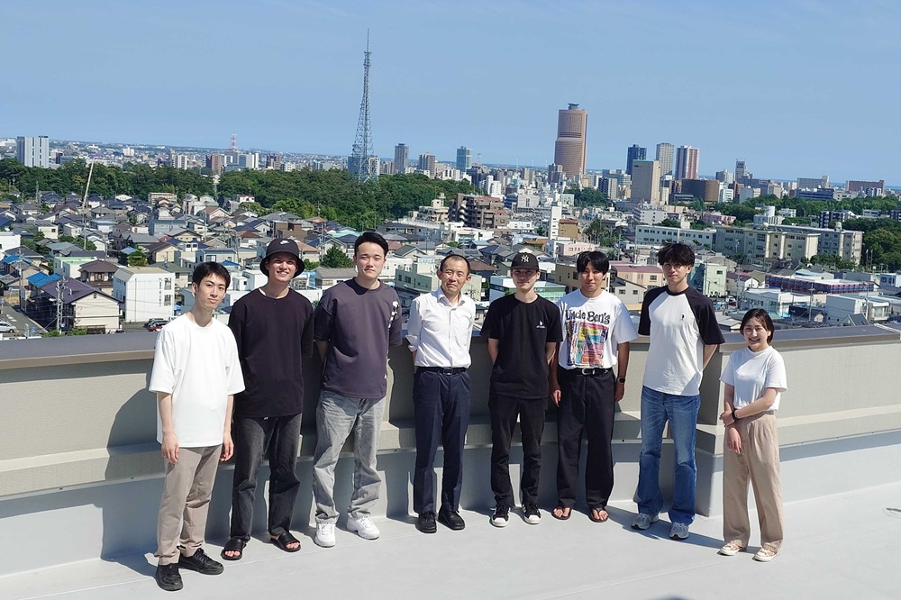 研究室のメンバーと。大学の屋上で、浜松市中心部を背景として撮影。