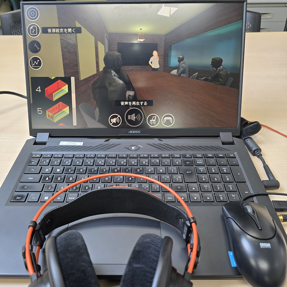 この写真は、私たちの研究室で開発した「物理シミュレーションに基づく空間音響シミュレーション技術」を用いて作成したVRコンテンツの一例です。会議室での会議のシーンを想定し、内装条件によって空間の音響がどのように変化するかを、実際に聞き比べることができます。

例えば、音響材料のある場合とない場合の違いや、音響材料をどこに・どのくらい配置するかによって、声の聞き取りやすさがどう変わるのかを体験できます。さらに、男性・女性の声、日本語・英語の音声など話し手や言語の違いによって、聞き手にはどのように聞こえるのかも体験できます。このプロジェクトでは、さまざまな空間を対象に、様々な音響特性を持つ音響メタマテリアルをどこに・どれだけ配置したら、どのような音環境をつくれるのかを、仮想空間上で探ることを目指しています。