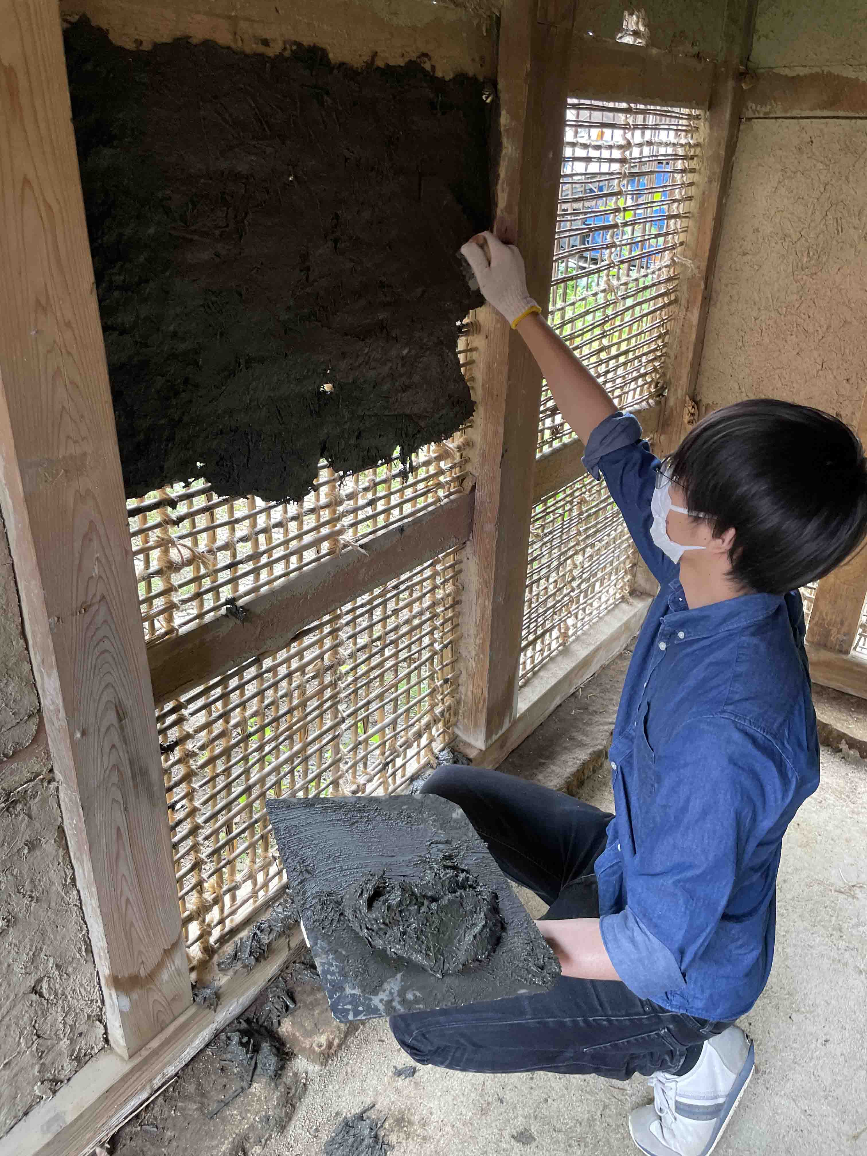 土壁の修復をしています。伝統的な住宅では土を塗って仕上げる土壁が用いられます。土に藁を混ぜ練り、竹を藁縄で編んだ木舞下地に鏝を使って塗りつけていきます。