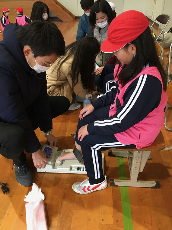 足指筋力測定風景。大学院生時代の後輩が教頭先生をしている愛媛県今治市の小学校で、全校児童の筋力や短距離走を測定しました。 写真は研究室の学生達が足指筋力を測定している場面です。約300名の測定を行いました。