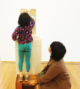 県内ゆかりの彫刻家の協力で展覧会を開催、彫刻家芝田典子氏の作品を鑑賞している子供と学生。