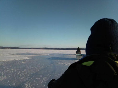 2021年3月、結氷した道東・厚岸湖の調査風景。スノーモービルにてけん引され調査地へ。（右端の後ろ姿が荒木）